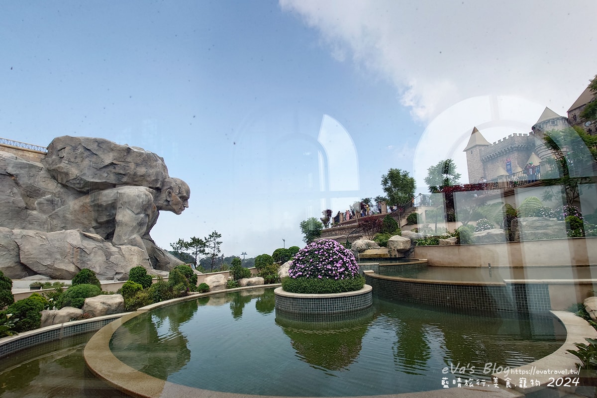 【越南旅遊】巴拿山 Ba Na Hills|法國村、黃金佛手橋、世界最長纜車,一座建在雲霧之上的空中樂園。越南景點 - 第60張圖 巴拿山城堡花園景觀與巨型石雕雕像,窗外可見水池與歐風建築